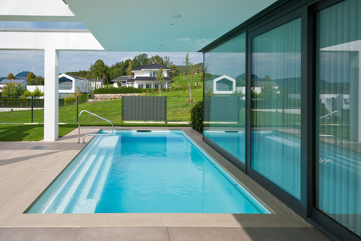 Outdoor-Pool mit einbetonierter Relaxzone sowie Sitz- und Liegeflächen.