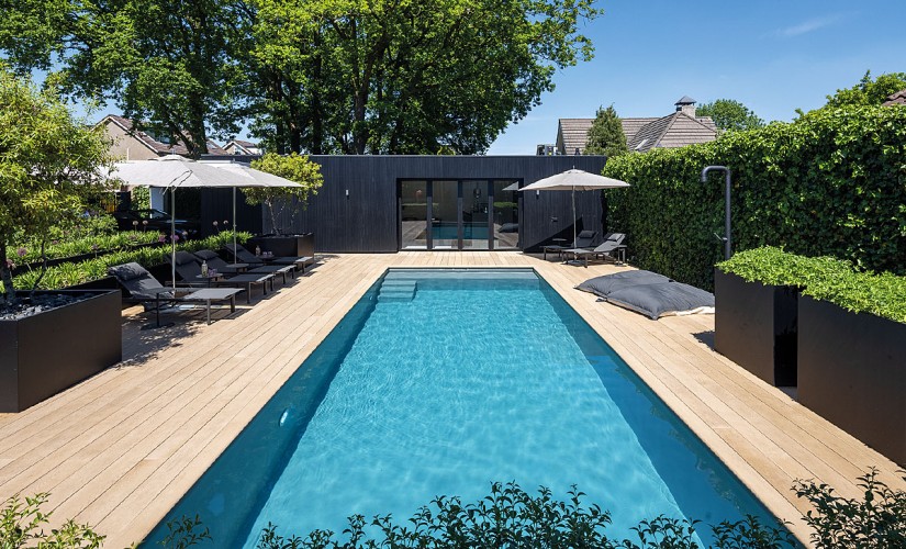 Ein Schwimmbecken vor einem modernen Gartenhaus.