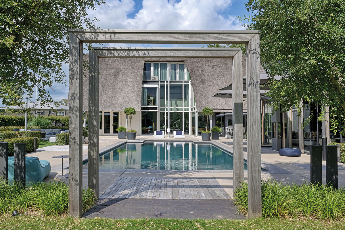 Blick vom Garten auf den Pool und das dahinterliegende Wohnhaus.