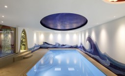 Schwimmhalle mit künstlerisch gestalteten Wänden.