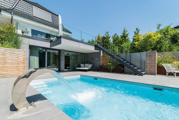 Ein Terrassenpool mit Schwalldusche vor einem Wohnhaus.